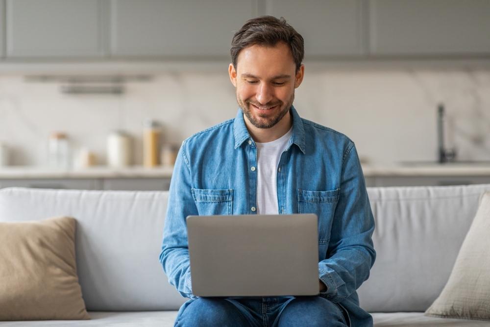 Man smiling using his laptop in an apartment